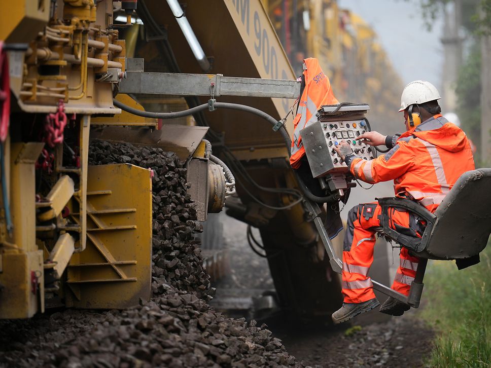 A construction worker operating a machine on the track.