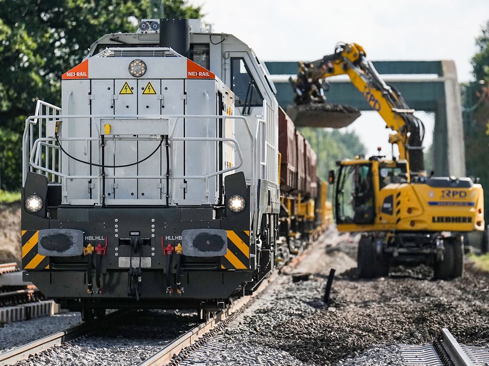 Lokomotive und Bagger auf einer Baustelle an den Bahngleisen