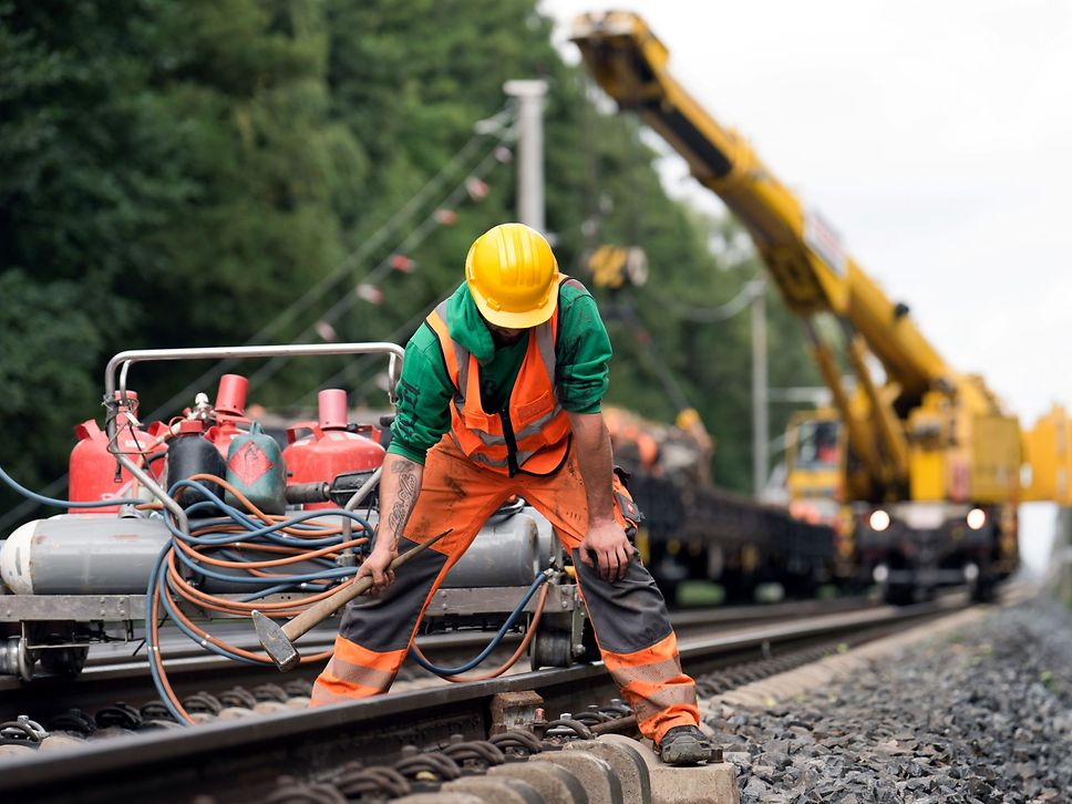 Zeigt einen Bauarbeiter der eine feste Fahrbahn ausbaut und verladet